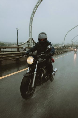 Blurred motorcyclist riding in the rain