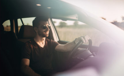 Man in sunglasses drives a car