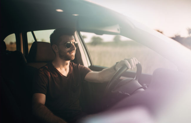 Man in sunglasses drives a car