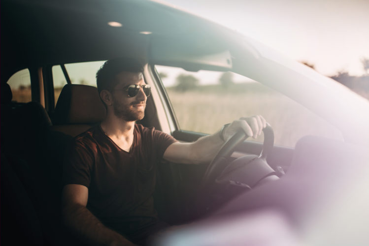 Man in sunglasses drives a car