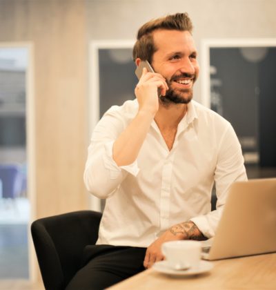 Man answers his phone while sat at his laptop