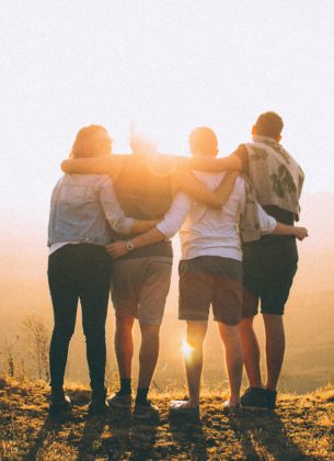 A group of friends stand looking out at the sunset