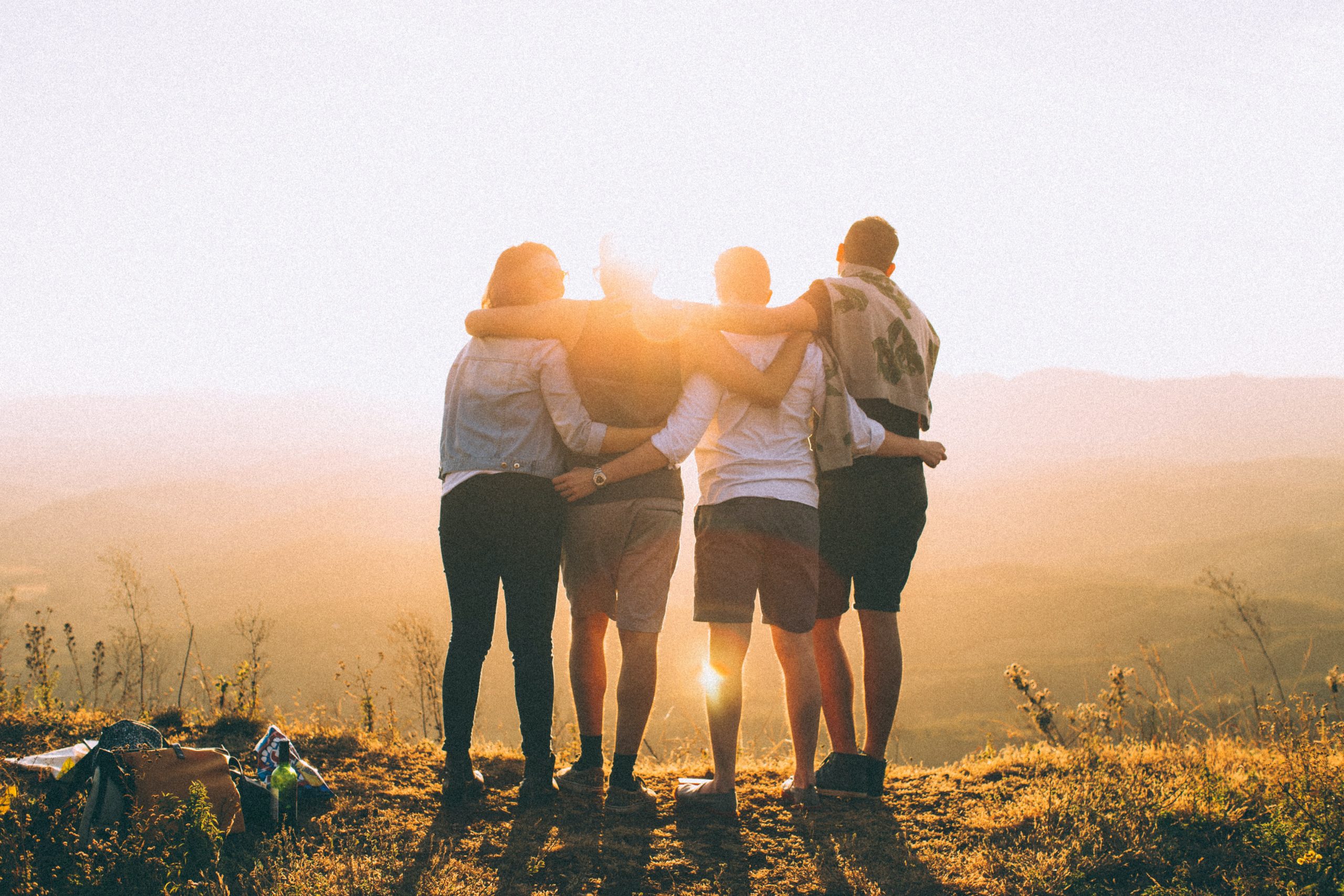 A group of friends stand looking out at the sunset