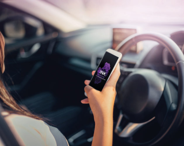 Woman loads the INK app on her phone while parked in a car