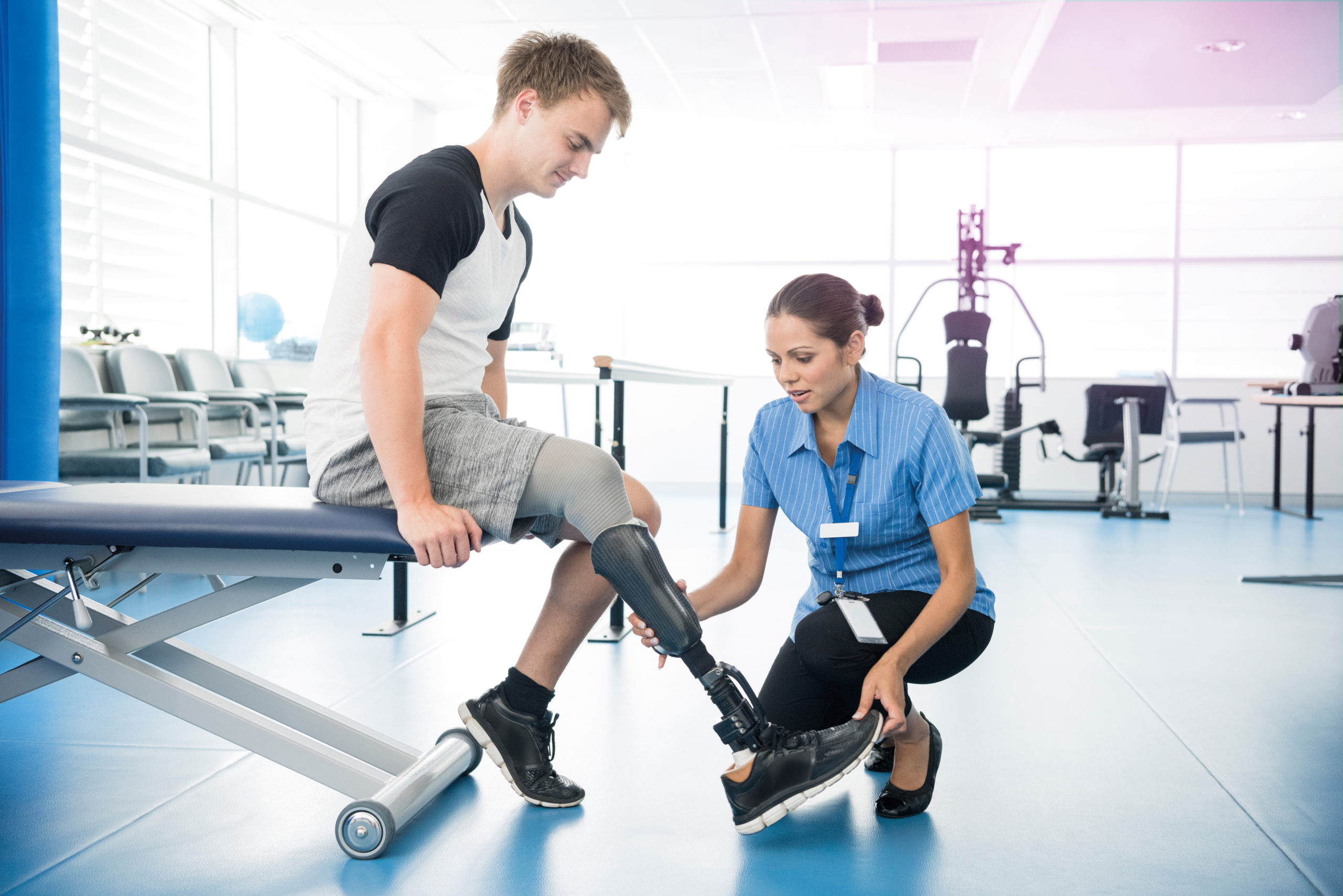 Patient sitting on bed with nurse holding prosthetic limb.