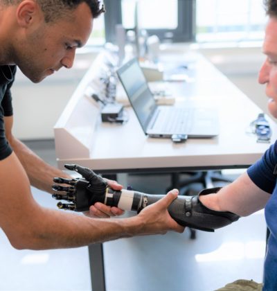 Physiotherapist helps a man to try out a prosthetic arm