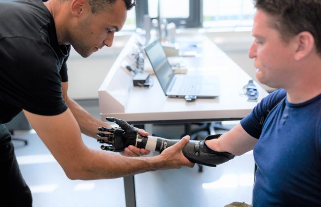 Physiotherapist helps a man to try out a prosthetic arm