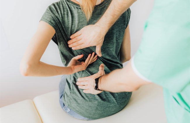 Physiotherapist takes care of a woman with back pain