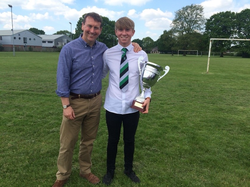 Steve with his son, who is holding a trophy, on the rugby pitch.