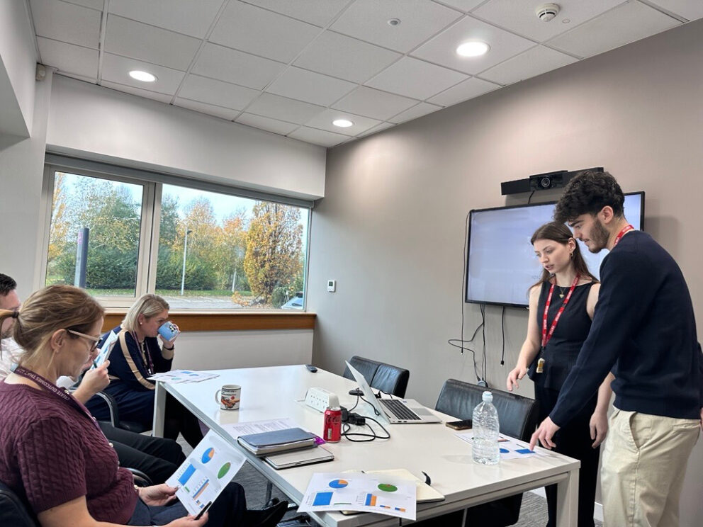 One male and one female student standing up in front of TV and having a presentation